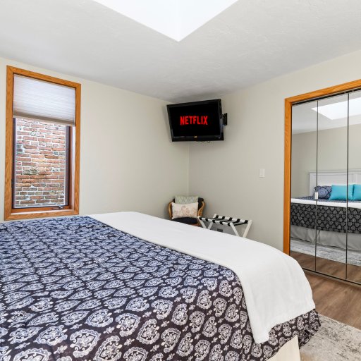 Bedroom 2 with wall-mounted TV and mirrored closet.