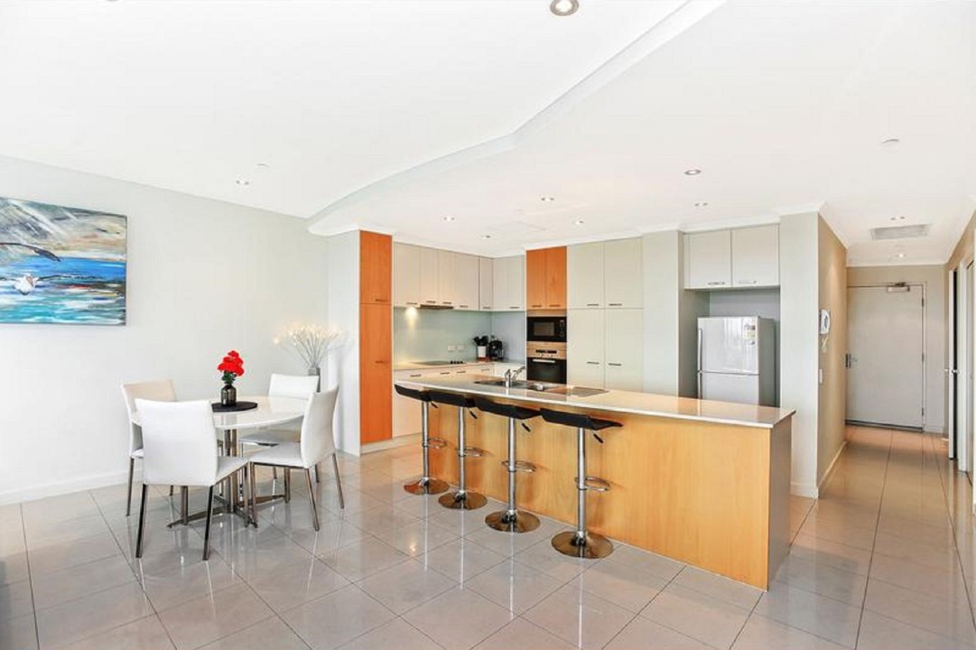 Modern island kitchen fitted with an electric oven, cooktop, range hood, and dishwasher, perfect for preparing meals in style.