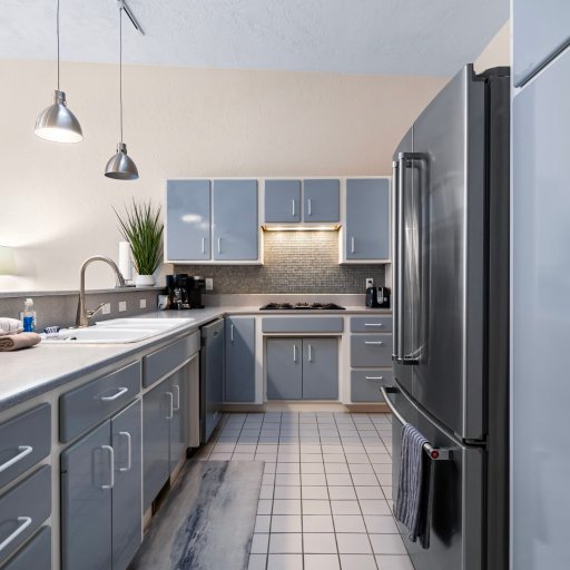 Galley kitchen with full-size fridge, dishwasher, and tile floor.