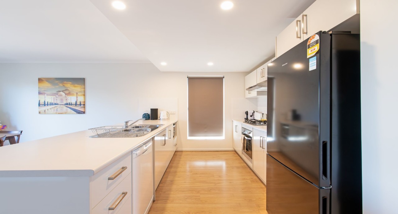 Fully equipped kitchen with Euro gas cooktop, electric oven, rangehood, and built-in dishwasher. Stainless steel appliances, ample cupboard space, microwave, kettle, toaster, and full crockery/cutlery set.