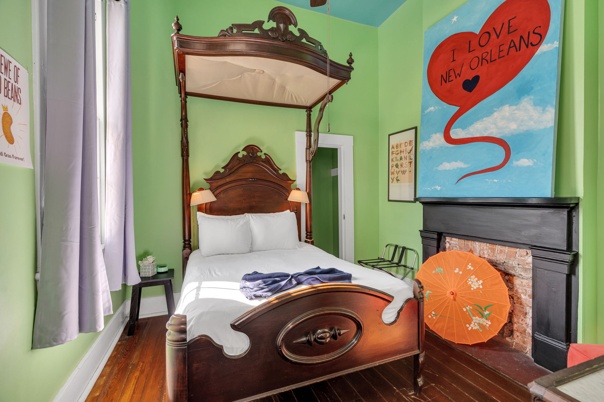 Vibrant NOLA bedroom featuring a grand four-poster bed, quirky art, and an original fireplace