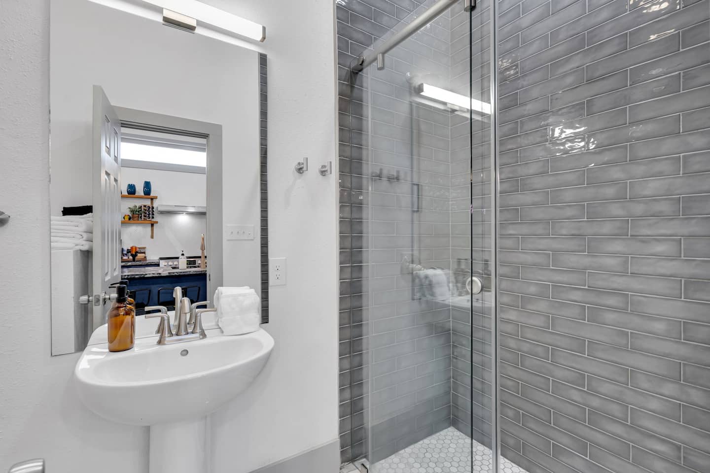 A sleek and modern bathroom featuring elegant gray subway tiles, a glass-enclosed shower, and stylish fixtures for a refreshing and luxurious experience.