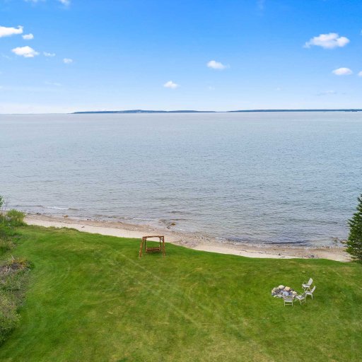 Elevated view over the shared lawn — lawn swing, fire pit, and the beach below