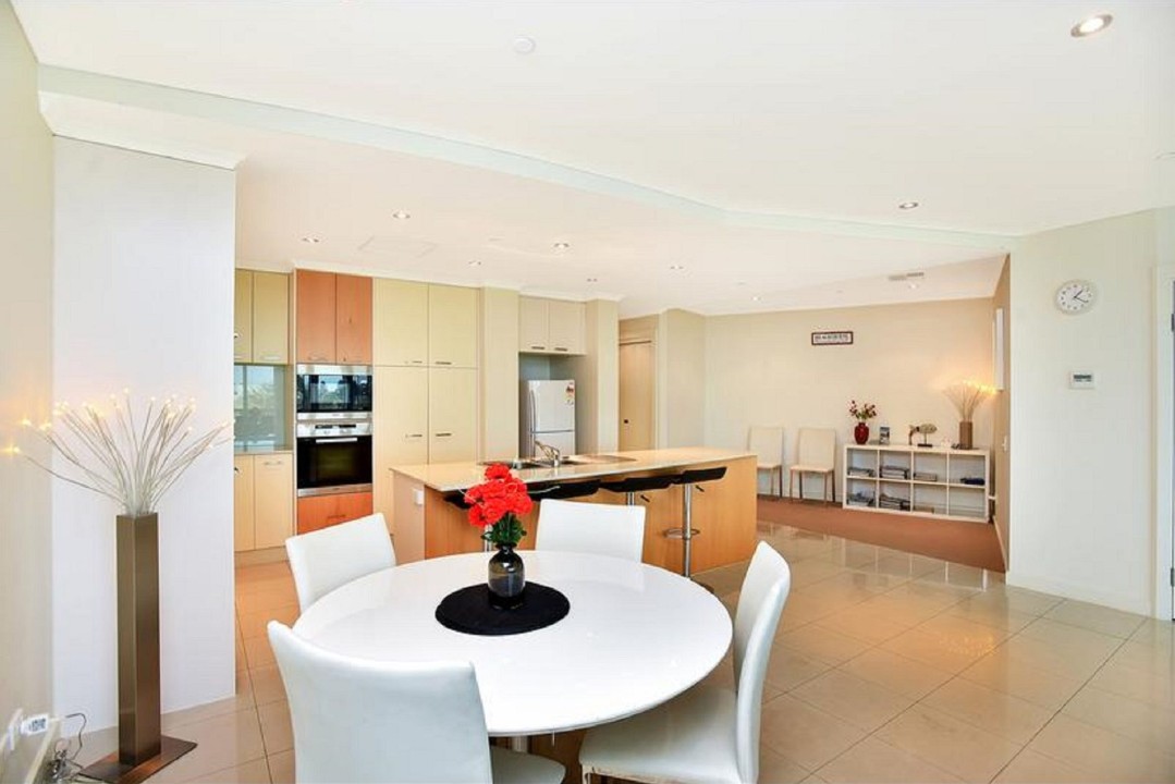Modern island kitchen fitted with an electric oven, cooktop, range hood, and dishwasher, perfect for preparing meals in style.