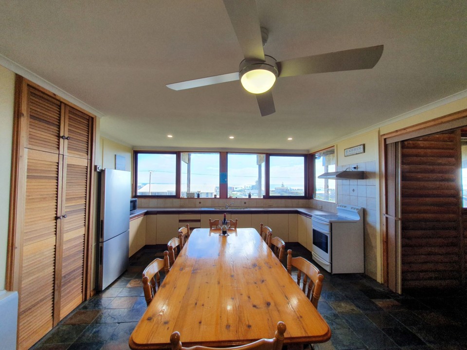 Includes a large front deck with sea views, a pergola-covered dining space, fire pit, paved and grassed backyard zones, outdoor shower, and a dedicated surfboard rack.