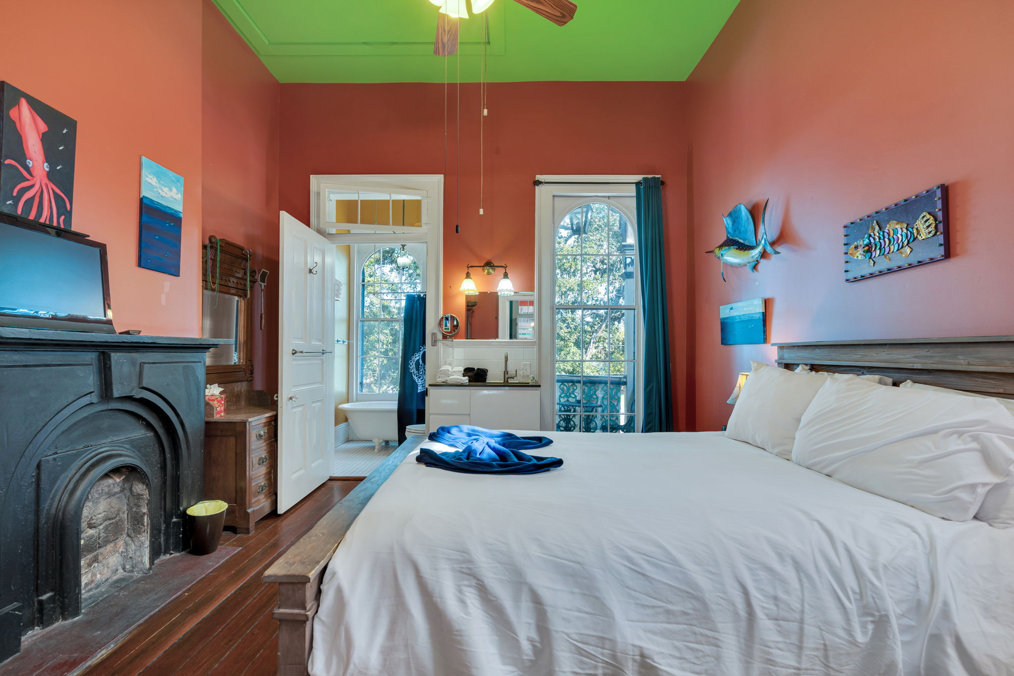 Relax in this airy bedroom featuring tall ceilings, abundant natural light, and a calming, art-filled atmosphere.