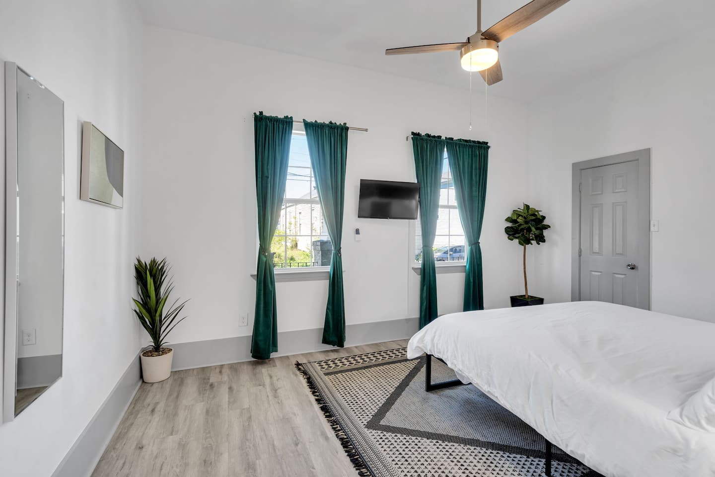 Relax in this cozy bedroom featuring a plush king-size bed, elegant decor, and rich emerald curtains. Enjoy a Smart TV, ceiling fan, and warm bedside lighting for ultimate comfort. Your perfect retreat awaits!