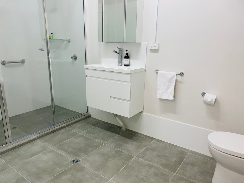 Features a stylish, updated bathroom with contemporary fixtures, a walk-in shower, vanity with storage, toilet, and quality towel sets provided. Designed for both comfort and function.