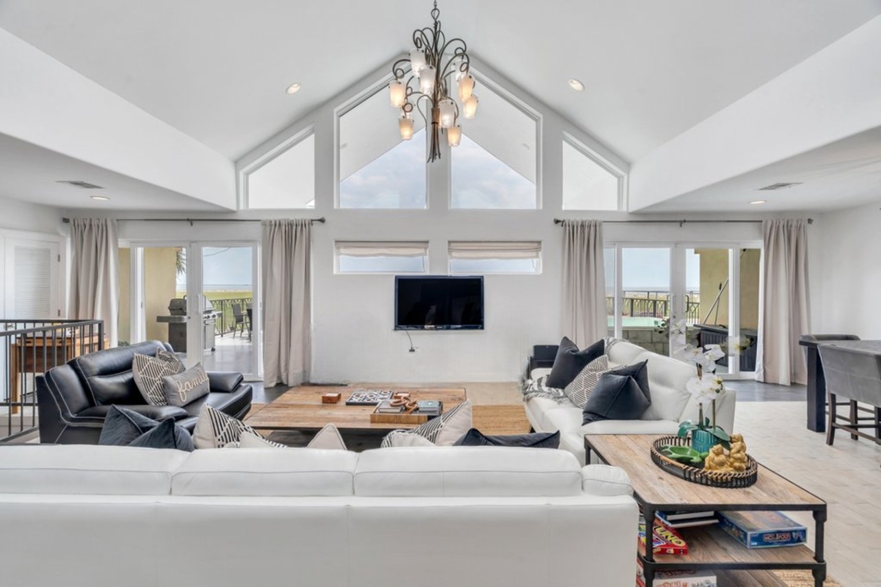 Living room featuring two large sofas, a chaise, dining for 10 at the table, and a full-service wet bar.