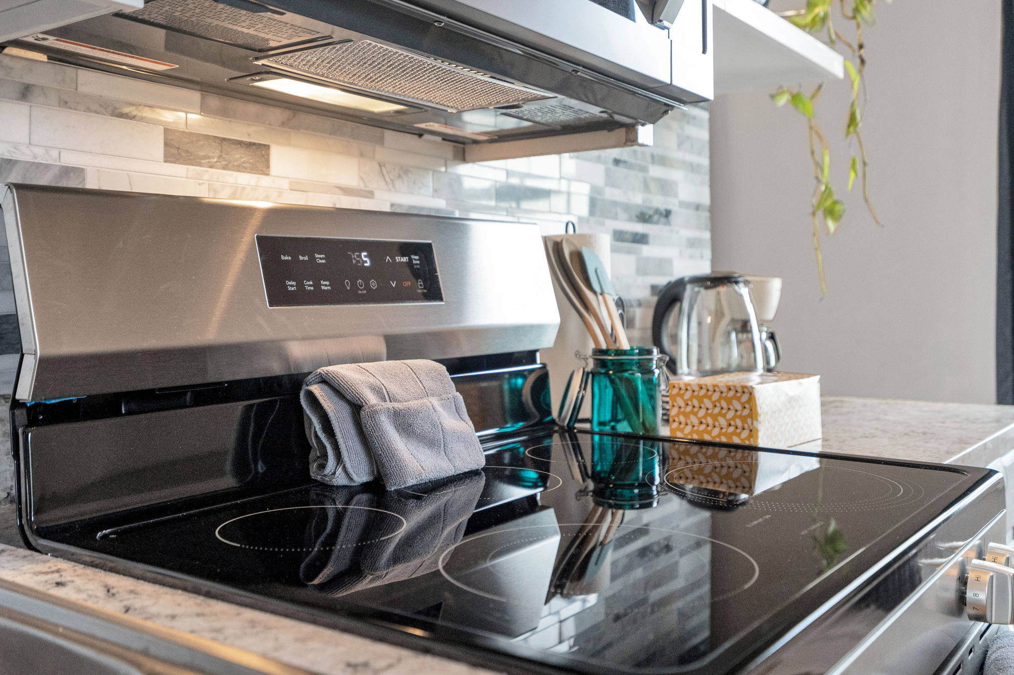Sleek electric stove with full cookware and stylish backsplash.