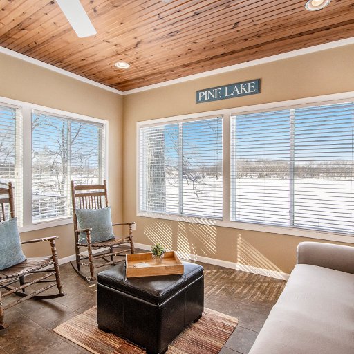 Sunroom with windows on three sides and rocking chairs facing Pine Lake