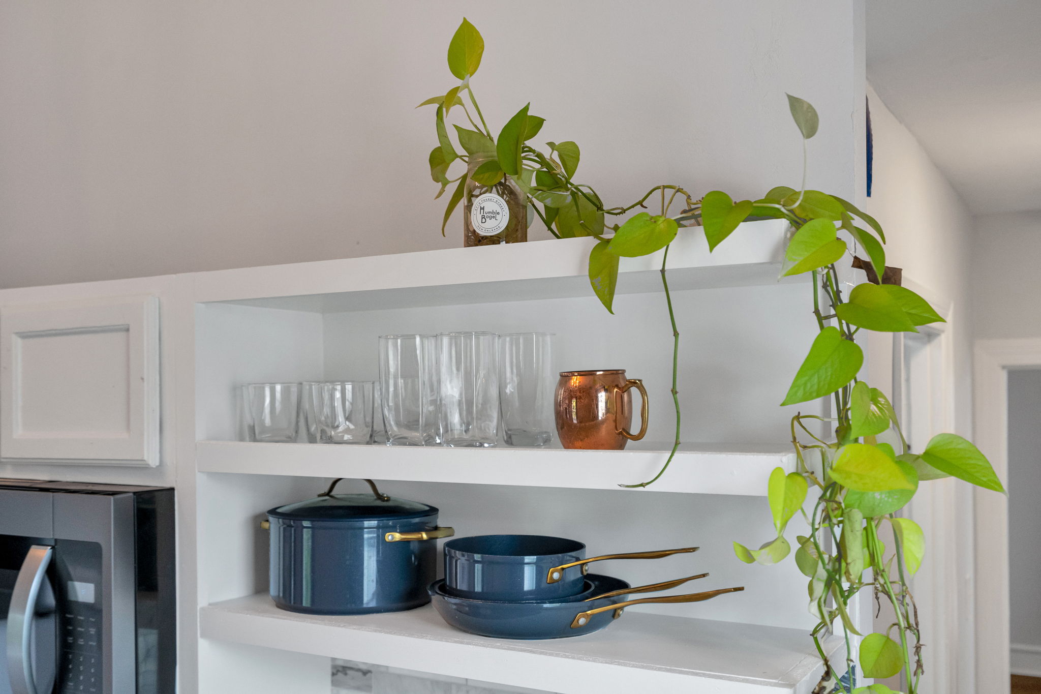 Open shelving with cookware, glasses, and greenery for a homey feel.