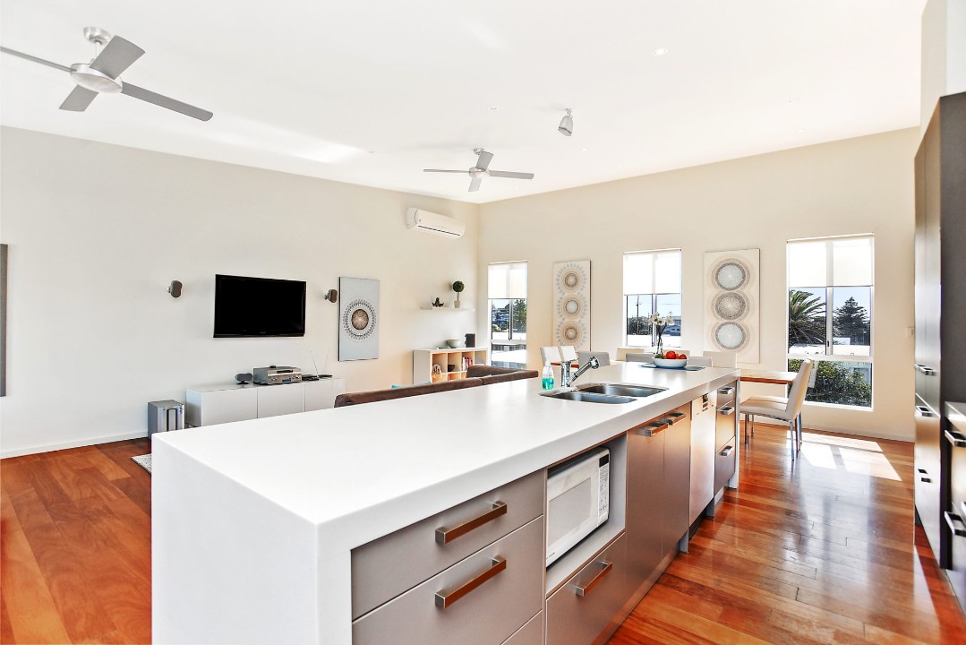 Includes dishwasher, oven, microwave, and essential cookware. Open-plan design connects kitchen to living area for seamless family interaction