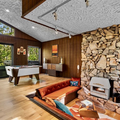 Floor-to-ceiling stone fireplace with peaceful forest views