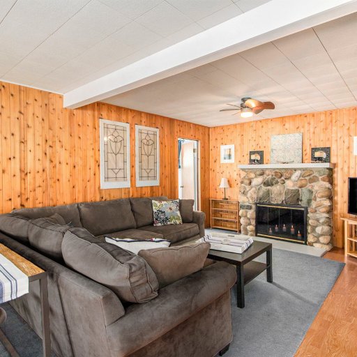 Living room with sectional, smart TV, and decorative stone fireplace