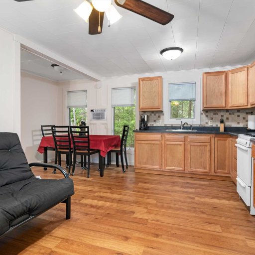 Open living, dining, and kitchen — futon sofa, table for four, and window AC