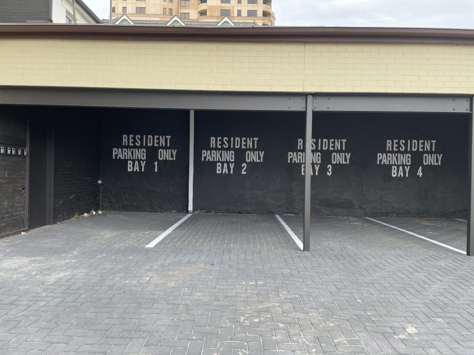 Parking is unnumbered, allowing flexible, first-come, first-served arrangements—including additional unnumbered spaces opposite the carport and under the outside stair area.