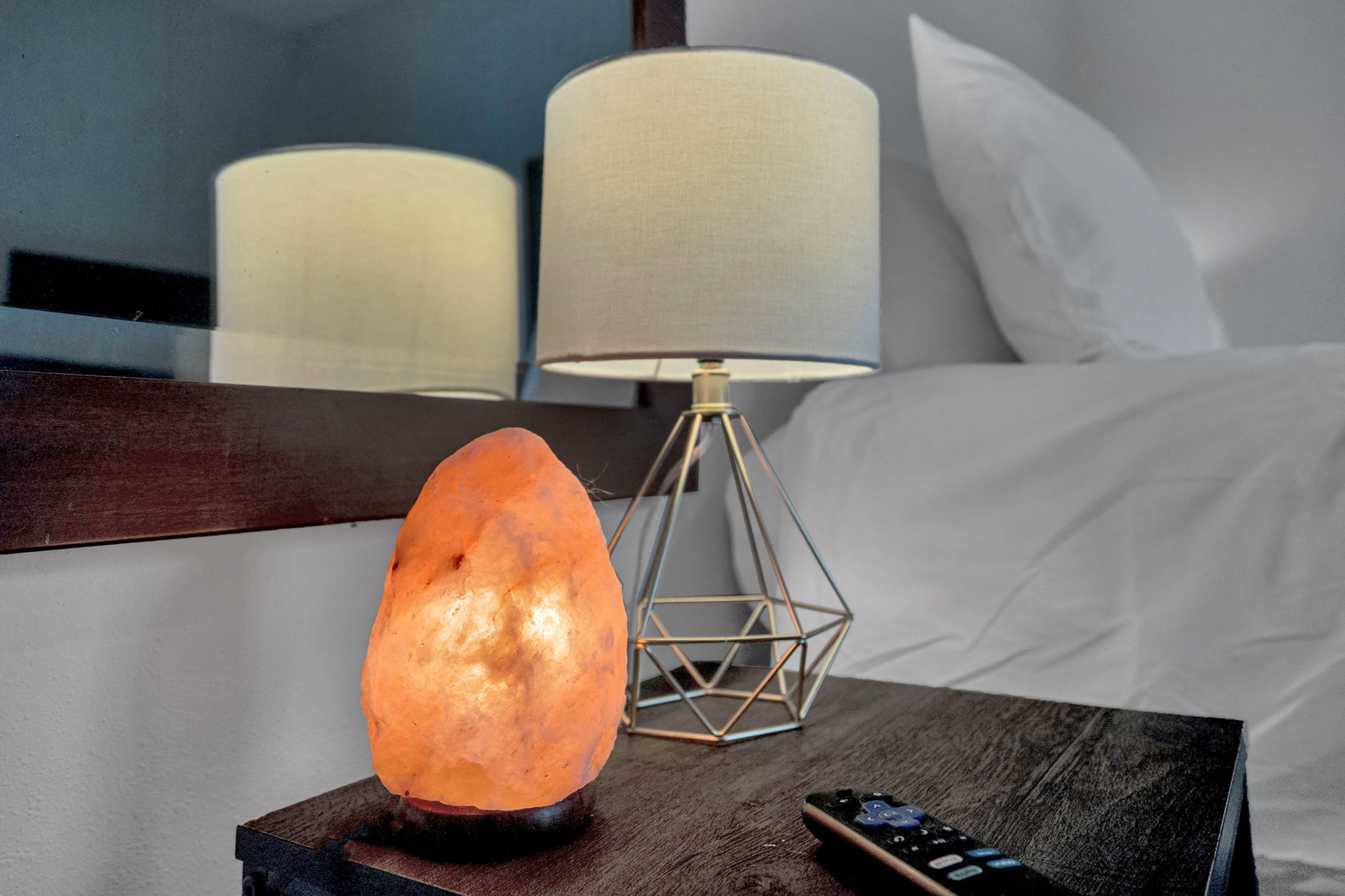 Warm bedside ambiance with salt lamp and modern lighting.