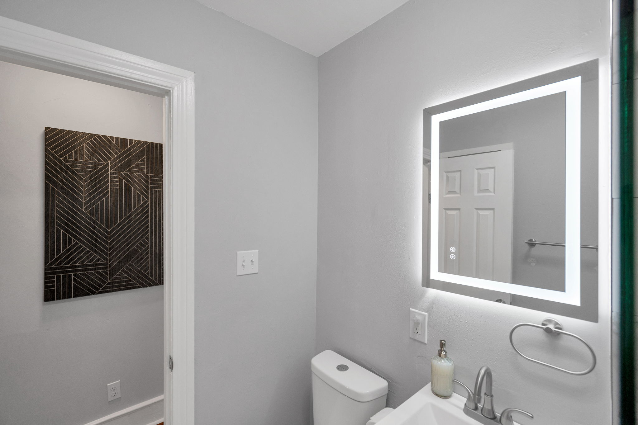 Clean, modern bathroom with bright LED mirror.