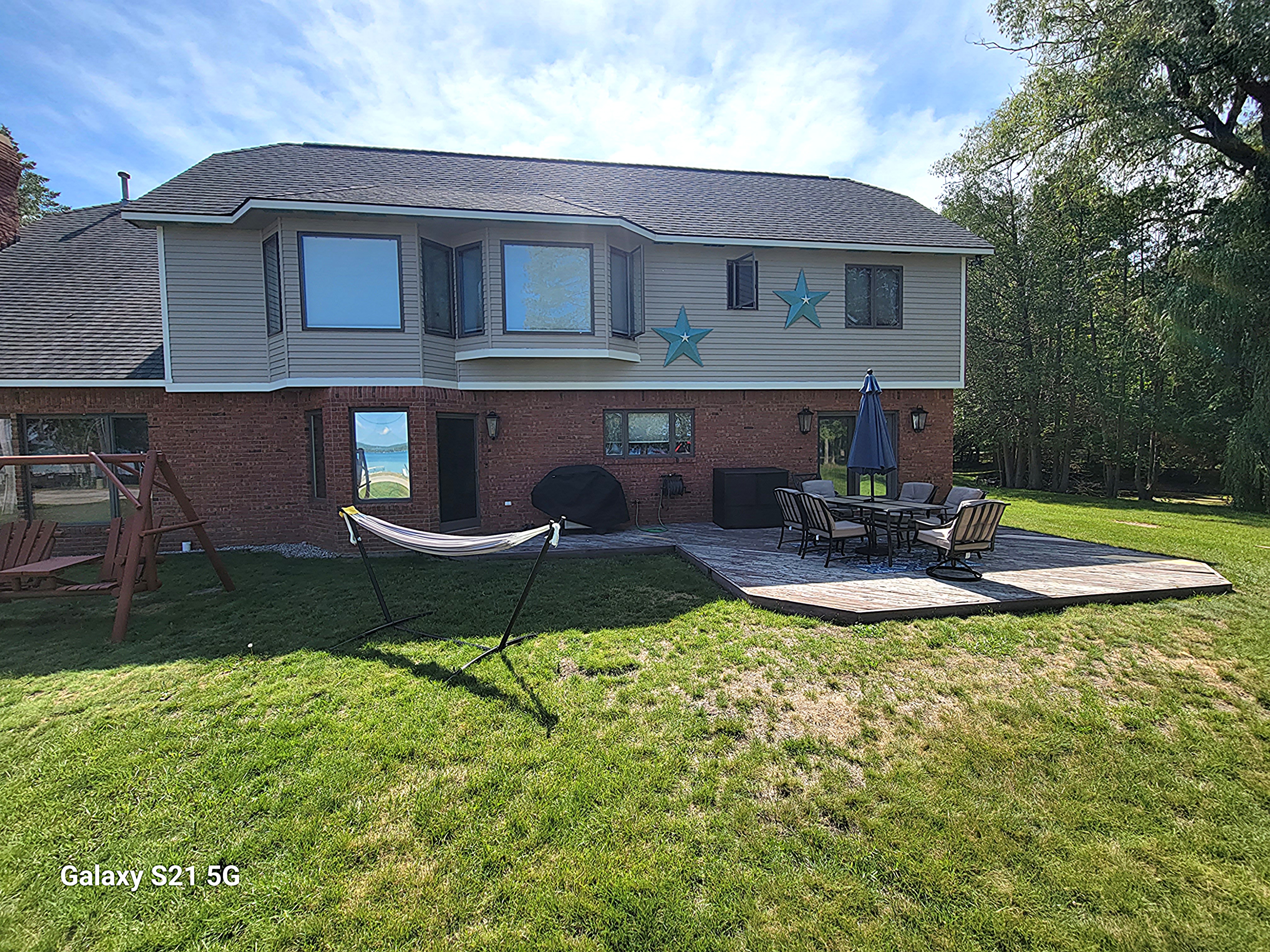 OVERVIEW:  The back of the home in the winter, showing the hammock, swing, and outdoor patio with outdoor dining furniture.