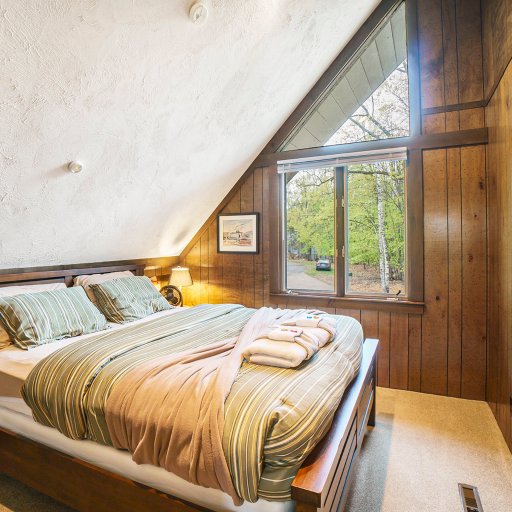 Inviting bedroom with a double bed, rustic wood paneling, and a warm, restful ambiance