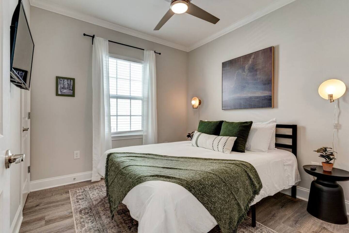 Cozy bedroom retreat featuring soft green accents, modern lighting, a serene ambiance, and a smart TV for your entertainment needs.