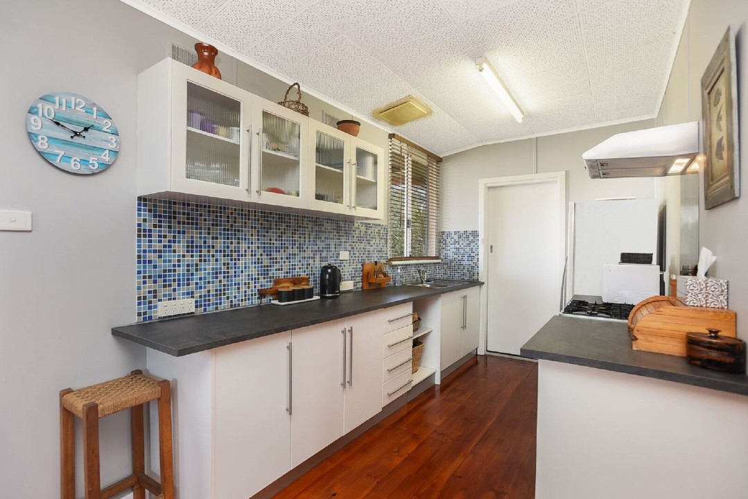 Functional galley-style kitchen with gas cooktop, oven, microwave, and large fridge/freezer – ideal for preparing home-style meals on holiday.