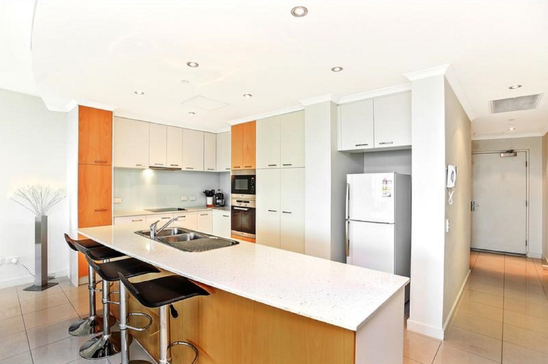 Modern island kitchen fitted with an electric oven, cooktop, range hood, and dishwasher, perfect for preparing meals in style.