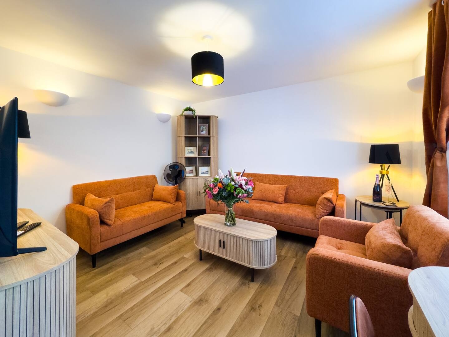 Stylish Social Lounge u2013 This inviting space boasts bold burnt-orange sofas, warm wooden flooring, a Smart TV with Sky, and colourful accents that brighten the space.