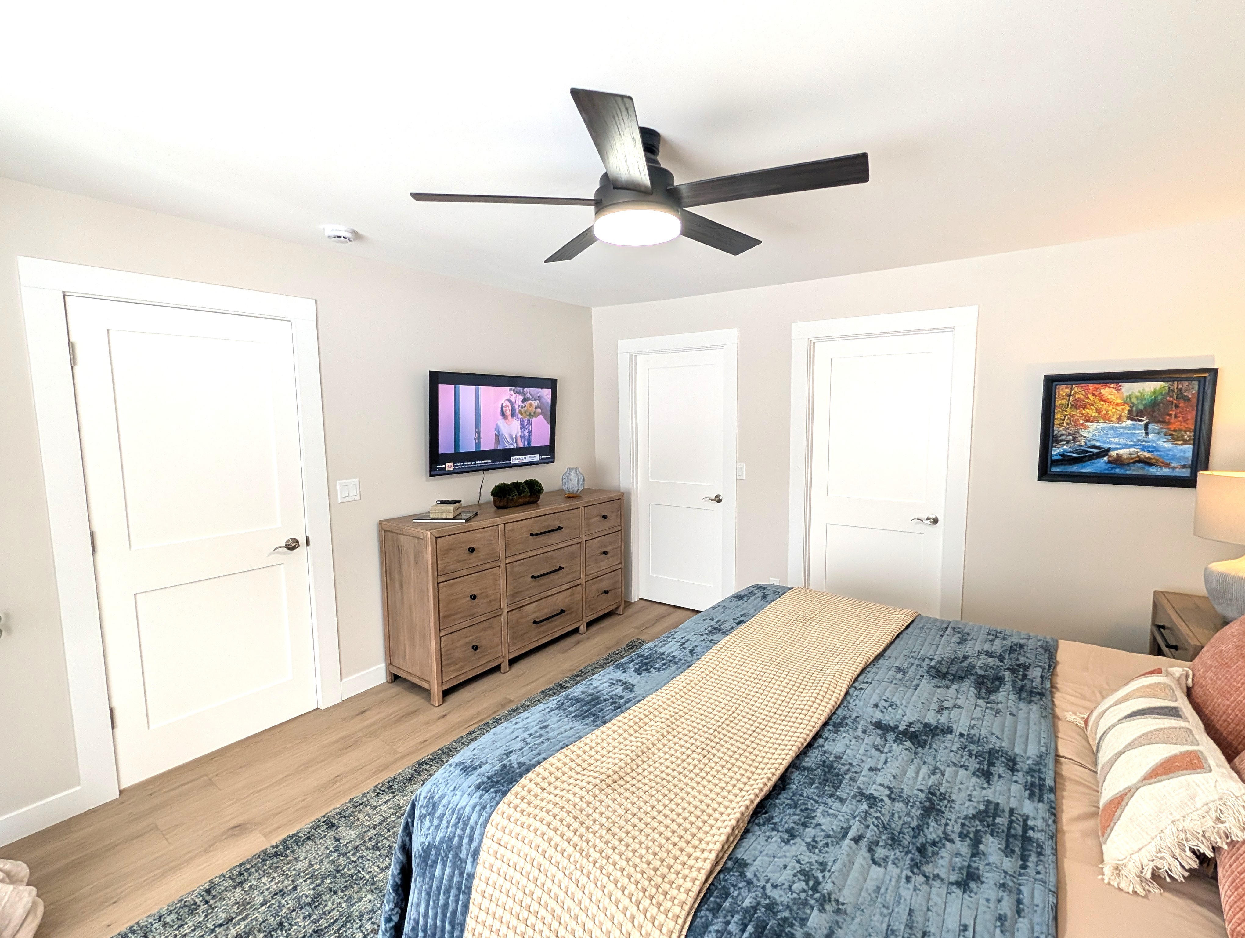 BEDROOM #1 (PRIMARY BEDROOM, MAIN FLOOR):  This is large and beautiful bed featuring a king-size bed, private ensuite full bathroom, private television, dresser, chair, ceiling fan, and closet.