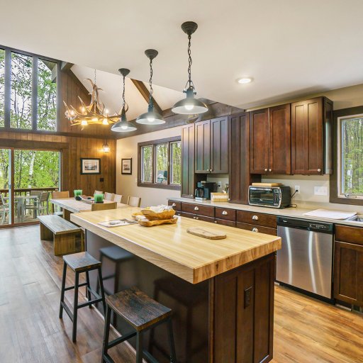 Butcher-block island with bar seating, opening to the deck through floor-to-ceiling windows.
