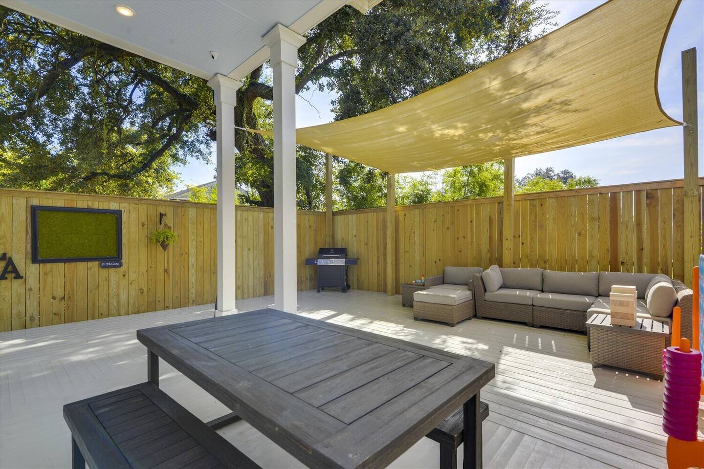 Shaded outdoor lounge with dining space and a grill—ideal for relaxing or entertaining.