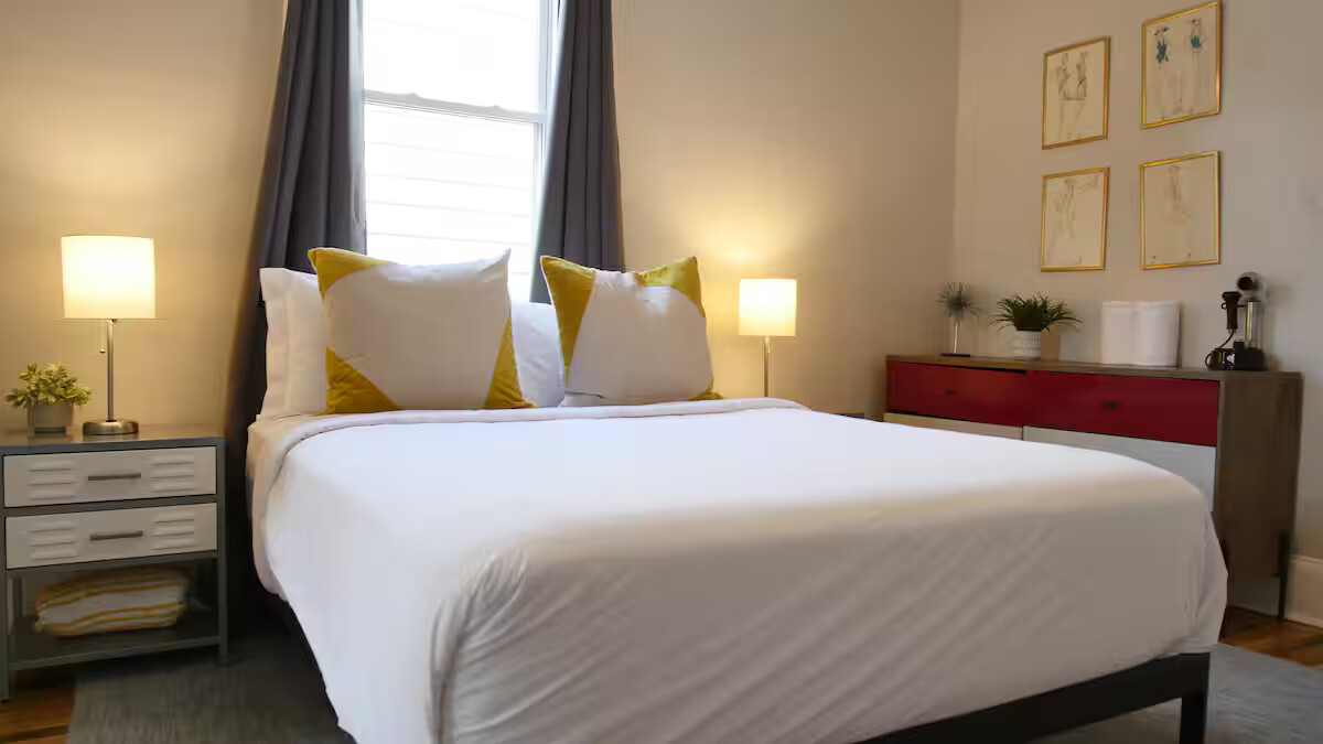 This bedroom is a serene retreat, featuring a cozy bed, soft linens, and a calming atmosphere, ideal for a restful night after exploring the city.