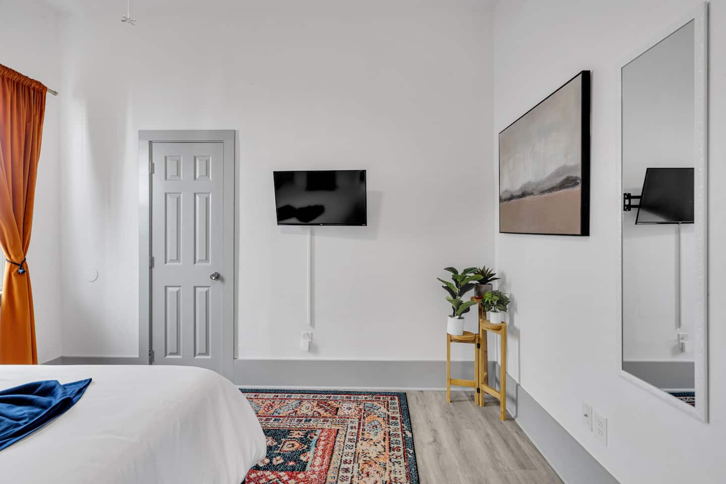 Unwind with a cozy bed, stylish decor, and a mounted TV. Soft lighting, warm curtains, and greenery create a peaceful, inviting vibe!