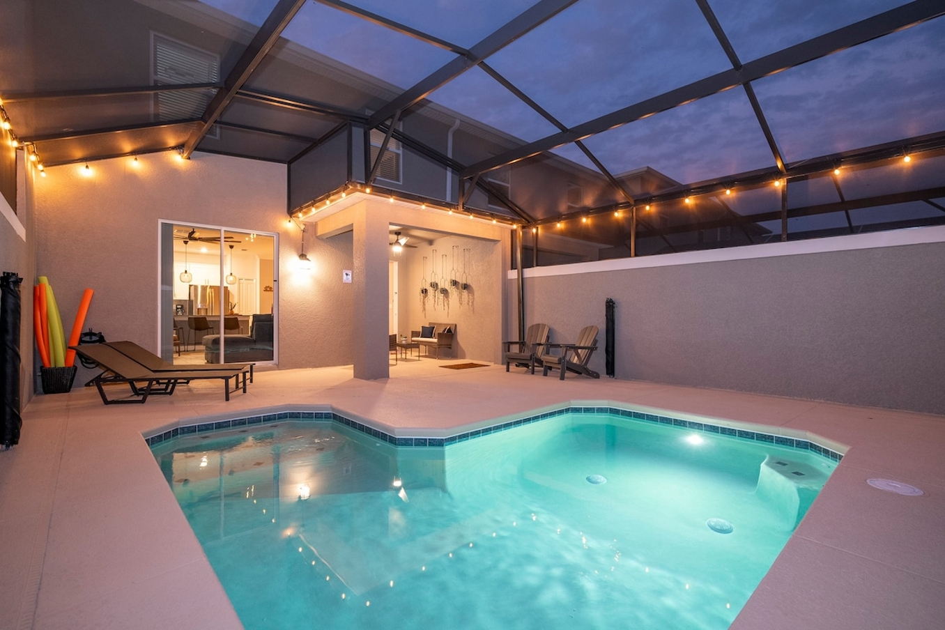 A spacious and inviting pool area, perfect for guests seeking that extra touch of luxury. The expansive pool, illuminated by the gentle glow of elegant lighting, offers a serene escape where you can unwind after a day of exploration. The cozy loungers provide the perfect spot to soak up the tranquil atmosphere, with every detail designed to make your stay an unforgettable experience. The screened structure keeps the area bug-free and comfortable, while warm lighting adds to the ambiance, creating a cozy and welcoming atmosphere. Direct access to indoor living spaces through sliding glass doors makes it easy to transition from indoor to outdoor living. This is the perfect place to relax and enjoy your vacation.