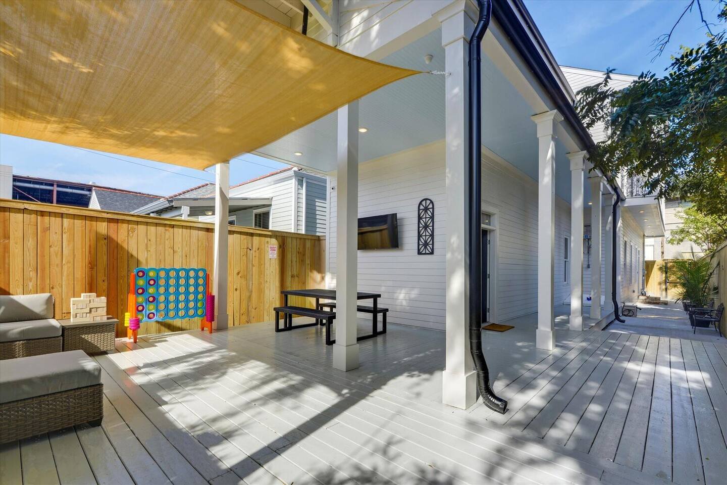 Covered patio fun with games, outdoor dining, and a mounted TV—perfect for all ages!