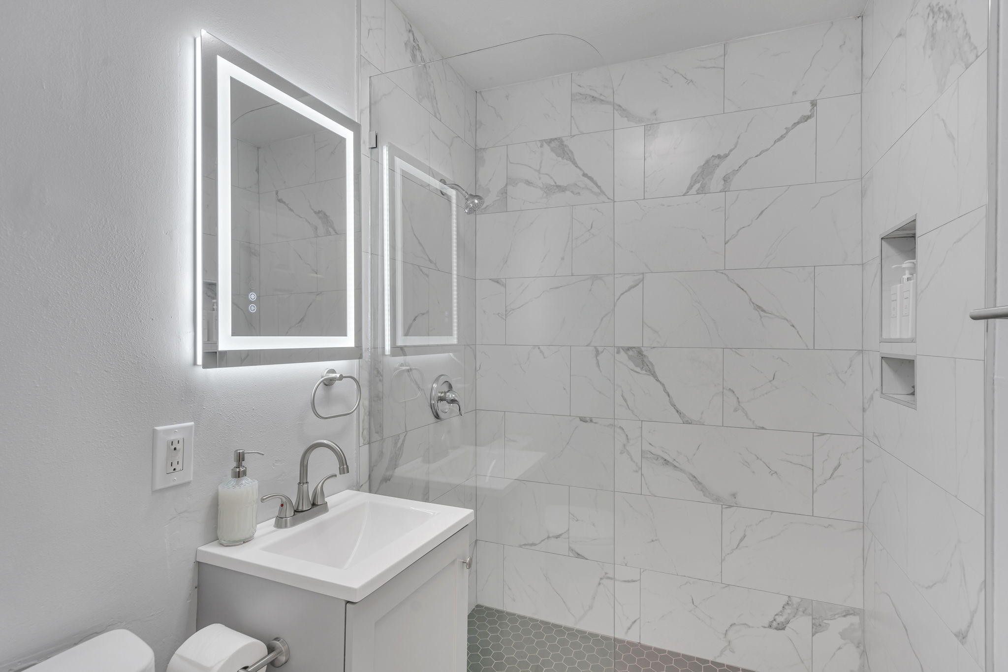 Stylish bathroom with walk-in shower and LED mirror.