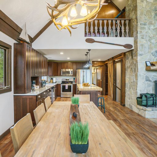 Enjoy meals surrounded by nature in the dining area, featuring a rustic antler chandelier and stunning woodland view