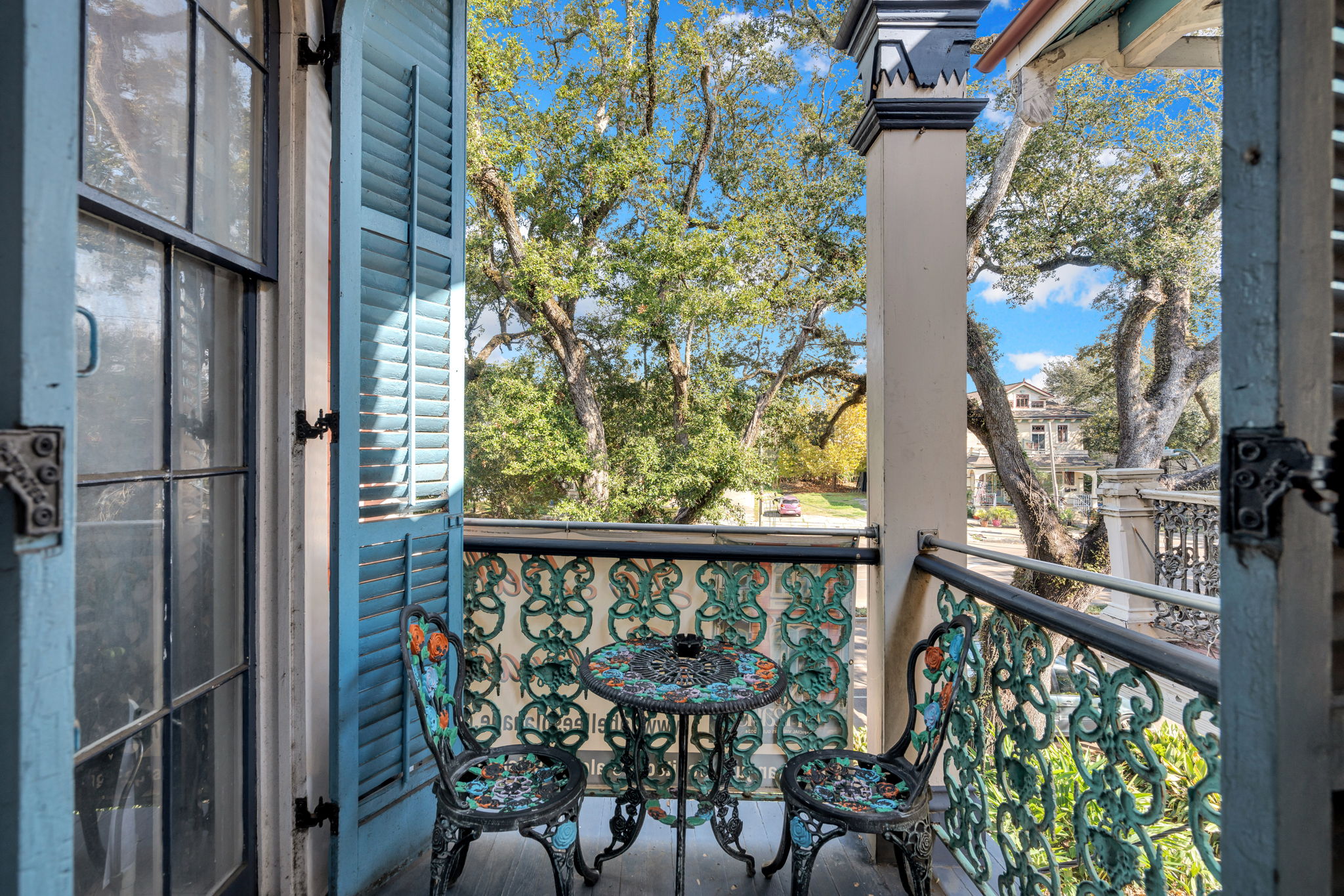 Charming balcony with ornate vintage furniture and serene street views.