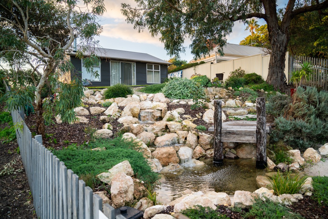 Private Outdoor Garden Oasis – A serene backyard featuring blooming flowers and a new waterfall, designed for peaceful moments and outdoor leisure.