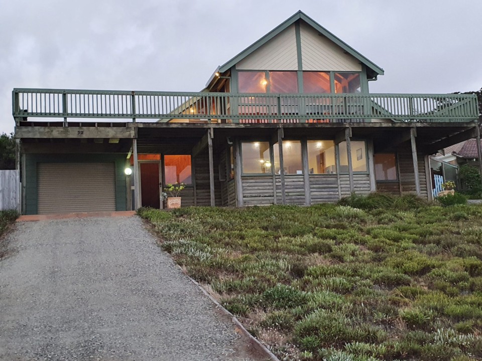 A two-storey design with high ceilings, open-plan living, and natural timber finishes creates a relaxed, homely atmosphere for coastal living.