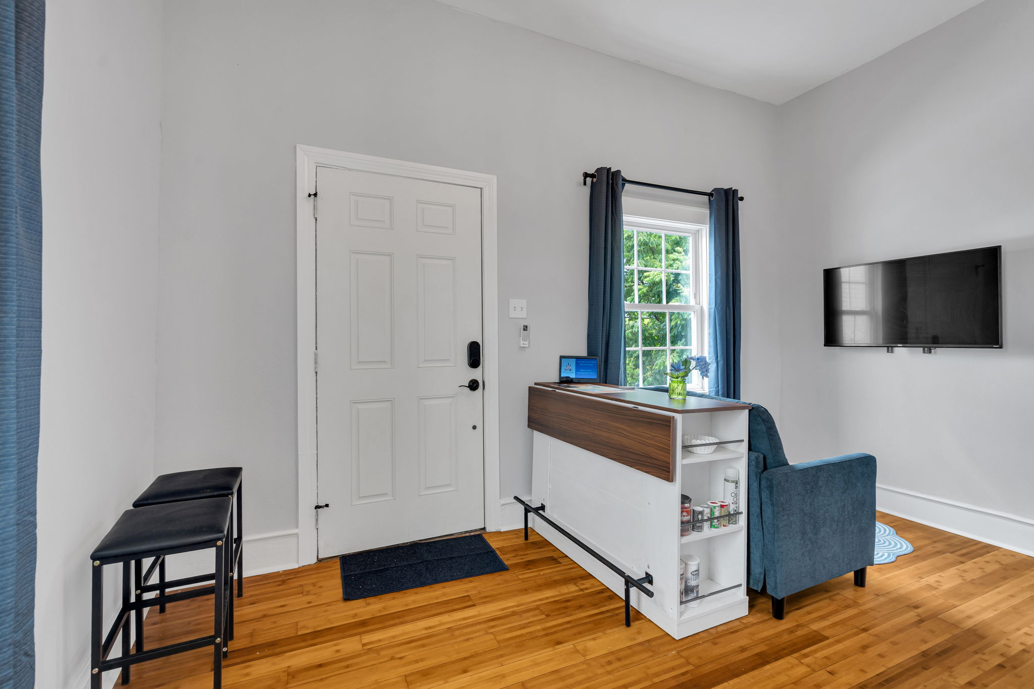 Bright entryway with a cozy sitting area, wall-mounted TV, and convenient breakfast bar setup.