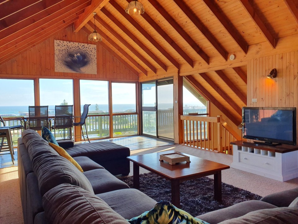 Multiple living zones allow guests to unwind together or separately—whether lounging upstairs, dining under the pergola, or soaking in the sea air from the deck.