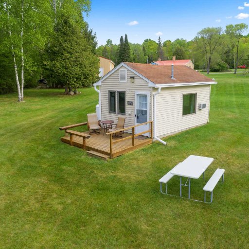 Cottage exterior with surrounding green space and lake nearby.