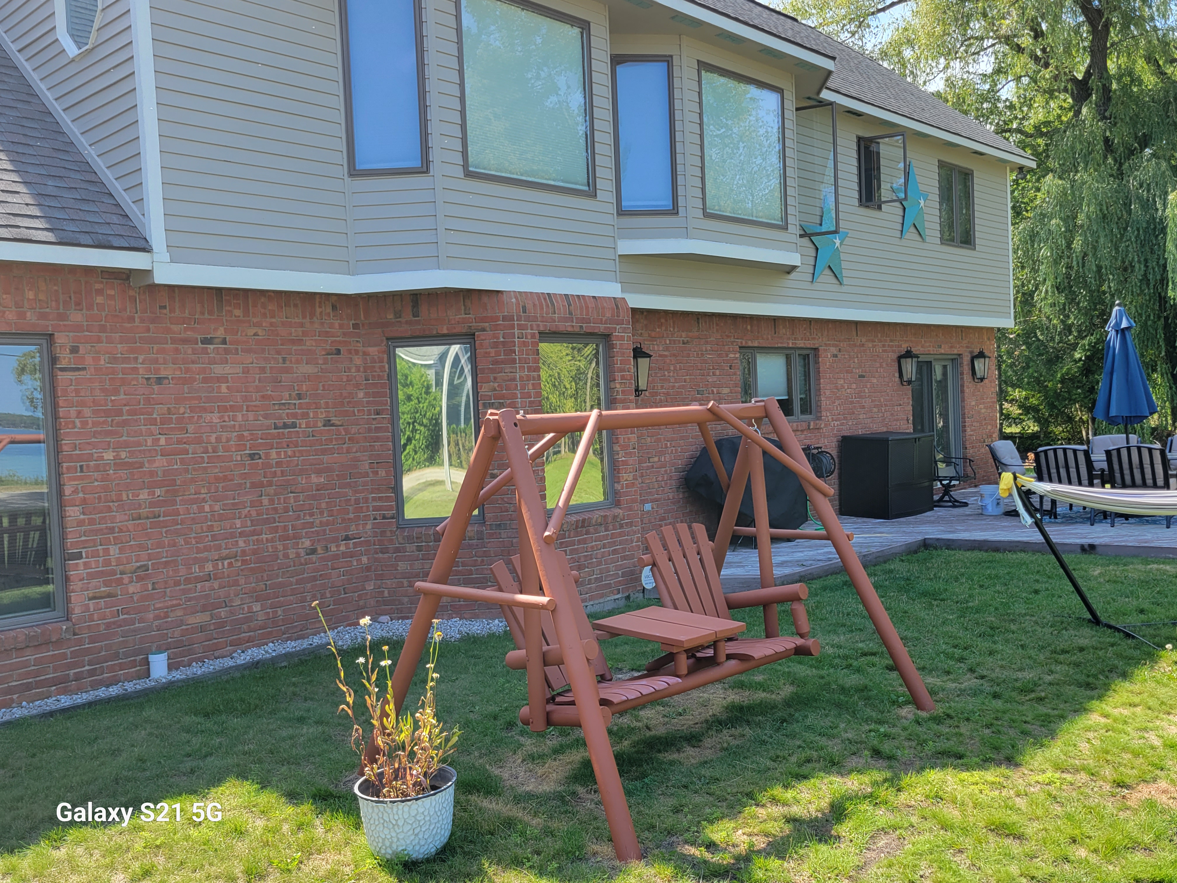 EXTERIOR:  Another view of the backyard, showing the swing, hammock, and outdoor patio.
