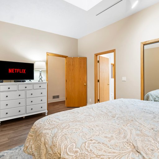 Bedroom 1: TV, dresser, and mirrored closet under a skylight.