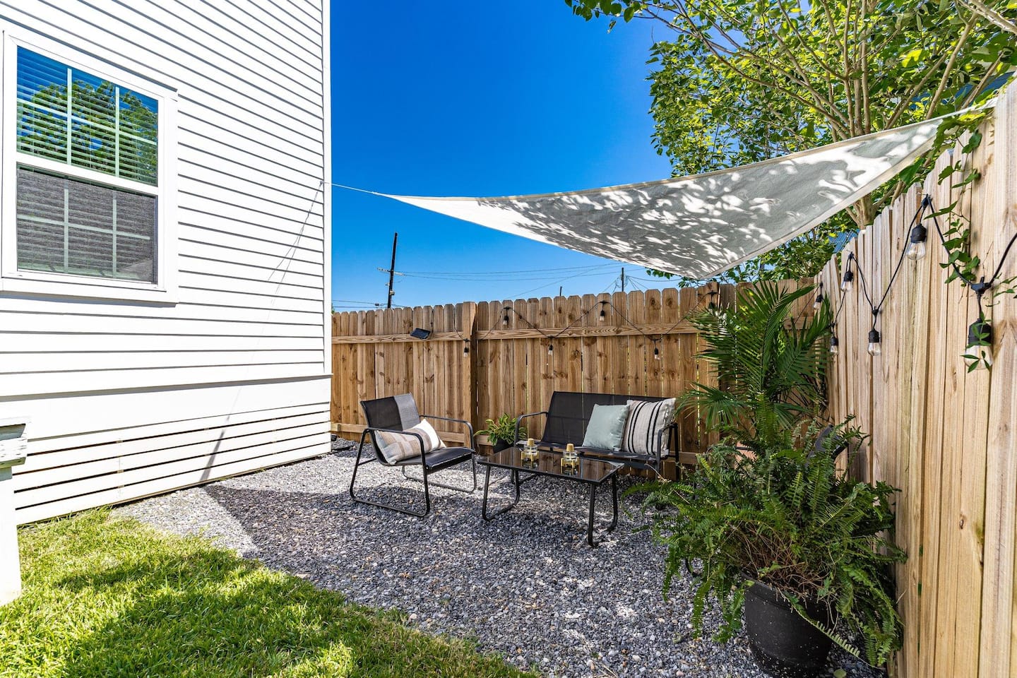 Relax in this private outdoor oasis featuring cozy seating, lush greenery, and a shaded canopy – the perfect spot to unwind under the New Orleans sky.