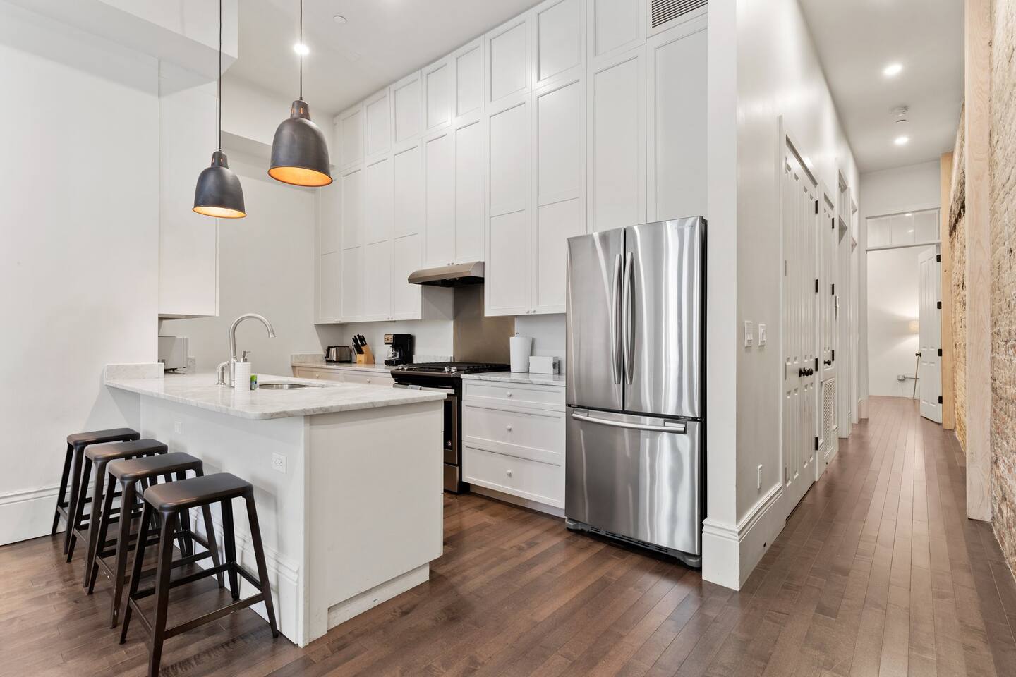 Kitchen space with bar seating and hallway leading to the bedrooms